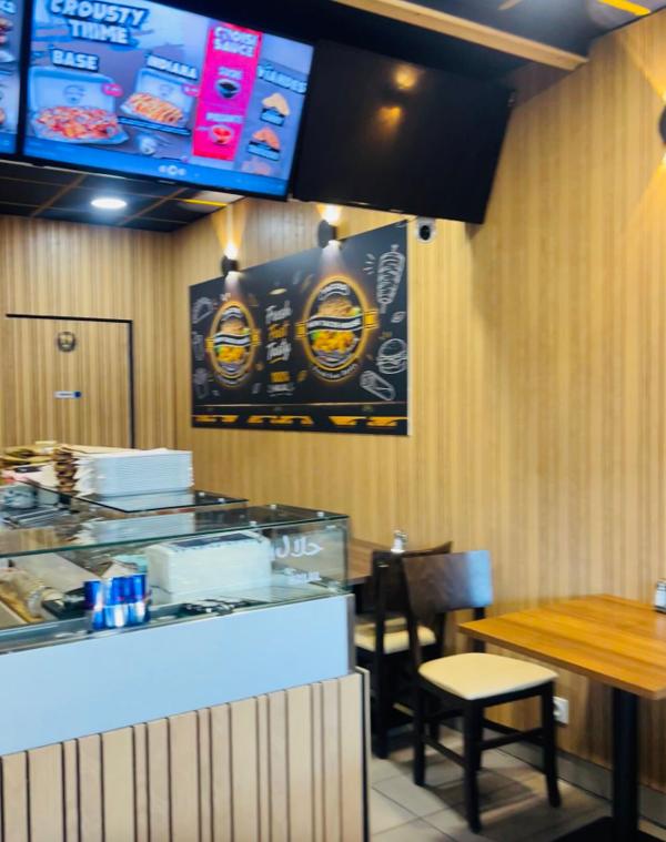 Comptoir vitré du restaurant, écrans de menus et espace pour manger sur place.