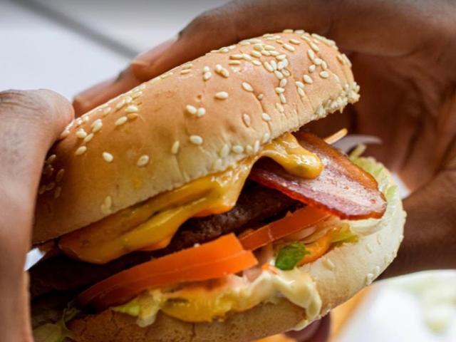 Burger dans un pain au sésame, avec fromage fondu, tomate et salade.
