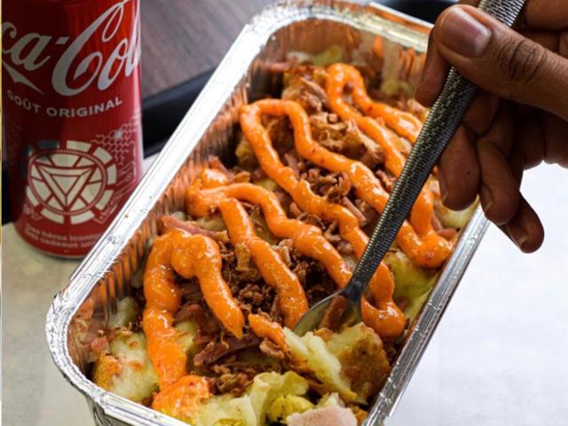 Kapsalon servi en barquette avec viande, fromage gratiné, salade et sauce.