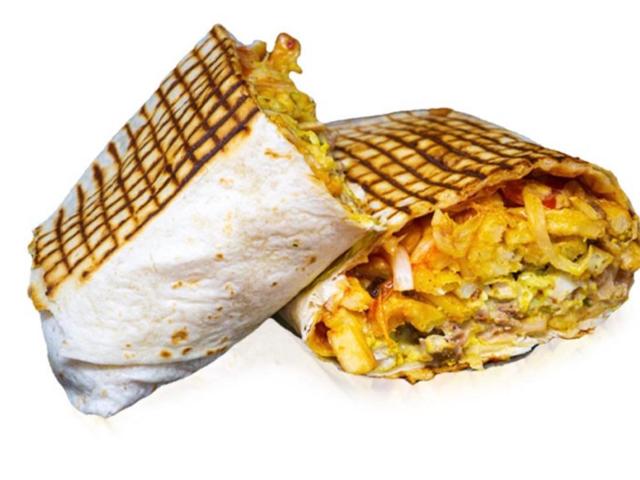 Tacos grillé coupé en deux, avec une garniture généreuse et des frites.